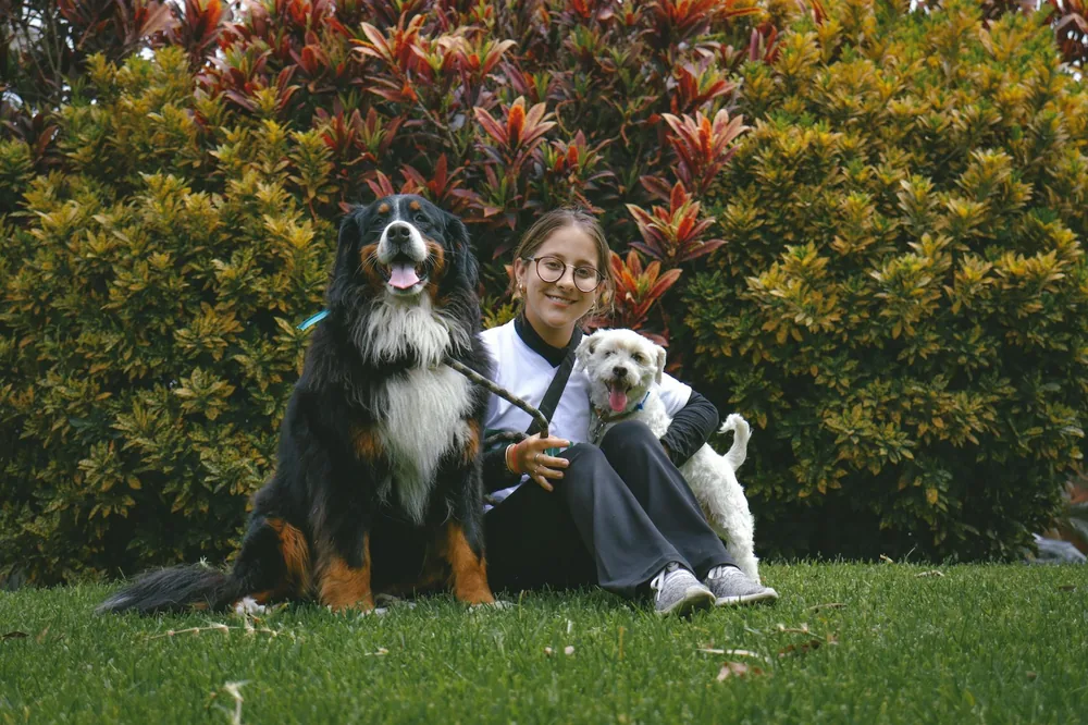 A smiling adopter in a garden with two happy dogs